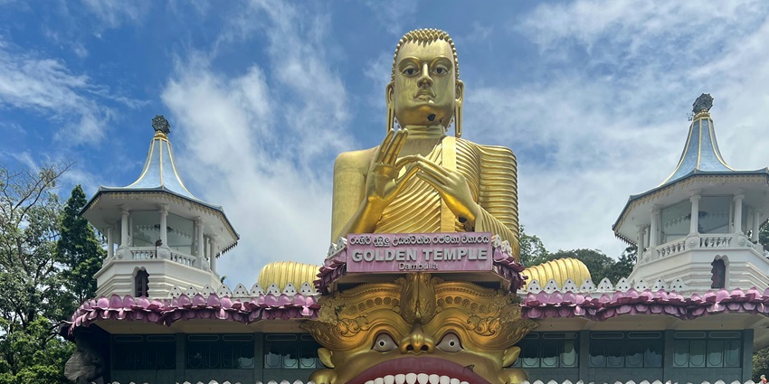 A view of the Dambulla Cave Temple entrance with rock formations and Buddhist statues.