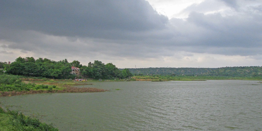 Damdama Lake featuring a restaurant on its shore, with peaceful waters and surroundings