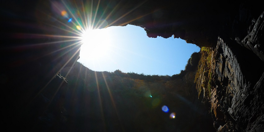 sunlight entering a cave, illuminating rock formations similar to Dark and Bright Cave.