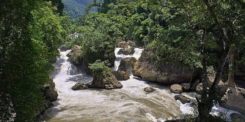 A breathtaking view of Dau Dang Waterfall, cascading through rocky terrains into a river below
