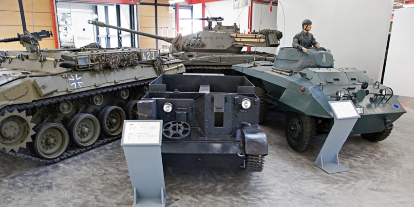 Military armored vehicles displayed indoors at a museum, with information plaques