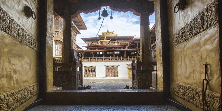 An image of an intricately carved temple entrance with ornate details, opening to a spacious courtyard
