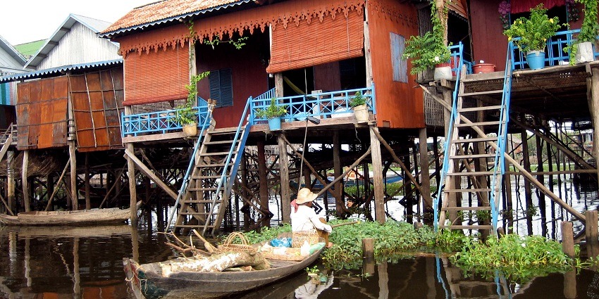 An image of colourful stilt houses over water, floating villages, adorned with potted plants, , one of the best things to see in Cambodia in April.