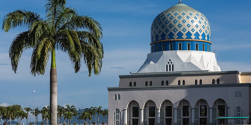 An image of the Kota Kinabalu City Mosque with blue-and-white domes and arched windows