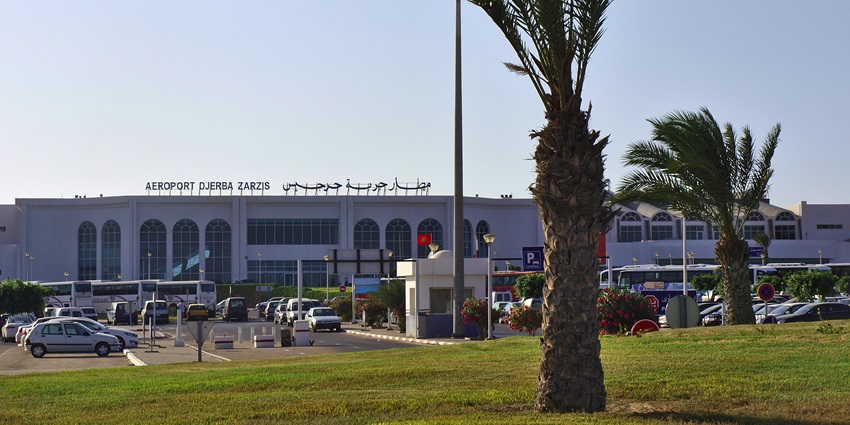 8Djerba-Zarzis International Airport with palm trees and parked buses and cars under a clear blue sky