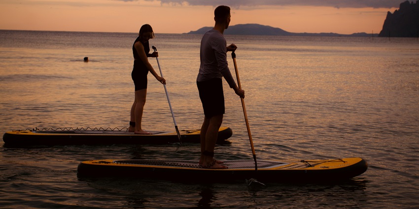 Image of a couple stand up paddle boarding during sunset hour - Things to do in Railay beach