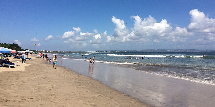 Colorful umbrellas, crowds, surfers, and beach bars create a scene at Double Six Beach.