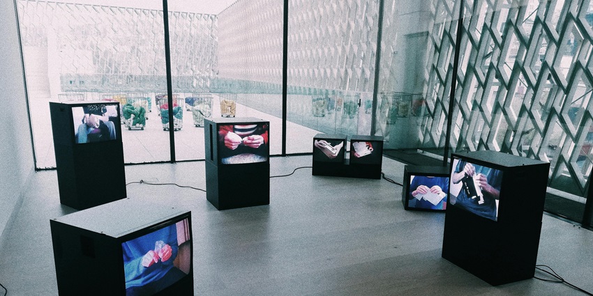 Interactive museum exhibit with multiple LCD screens showing educational content, arranged neatly in a dark, modern display area for visitors.