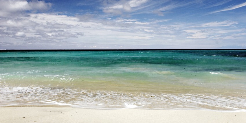 Dreamland Beach with white sand, turquoise waters, rock formations, and a stunning sunset.