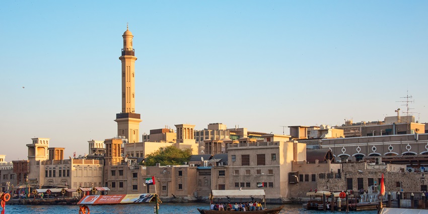Abras ferry passengers across the Dubai Creek, with historic building and a mosque minaret
