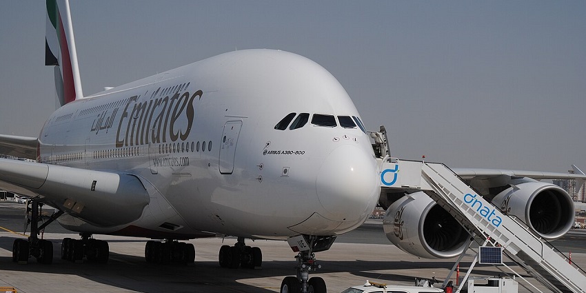 An image of an Emirates Boeing 777-300ER at Dubai International Airport, parked on the tarmac