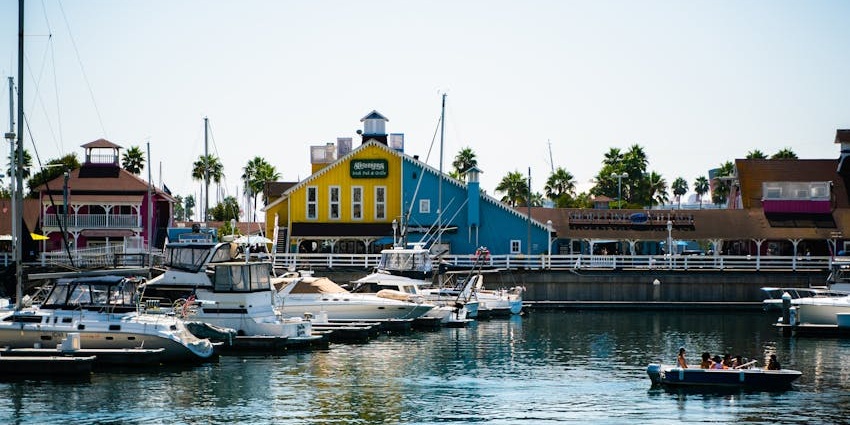 Image of boats docked in a harbour clear water with colourful houses beside during day time