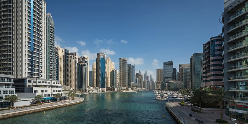Modern waterfront district in Dubai with luxury yachts, high-rise towers, beach clubs, and scenic promenade views, situated near gurudwara in Dubai.