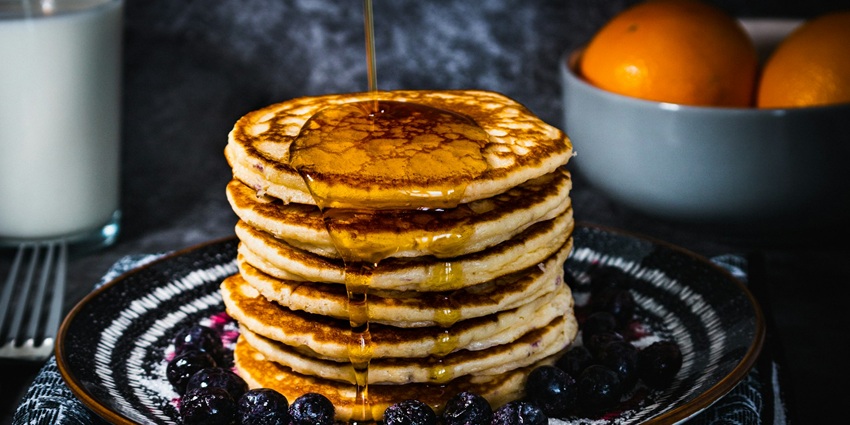 An image showing a delicious pancake topped with sliced strawberries, ready to be served.