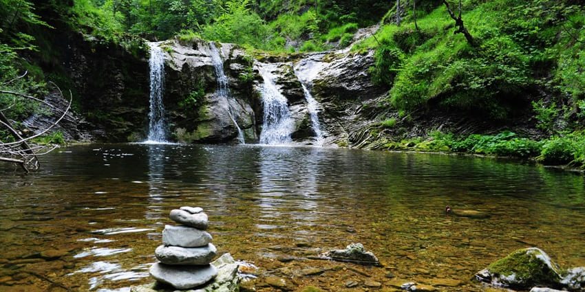 Small waterfalls in Pune with water flowing on a small rocky surface and mountains
