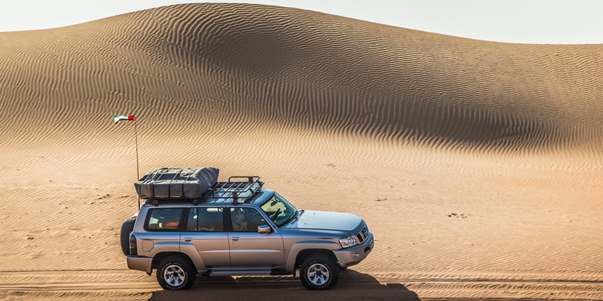 A scenic view of a car standing in the middle of the desert in Ras Al Khaimah under a cloudy sky