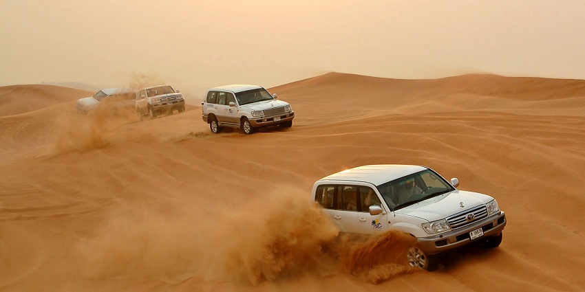 Vehicle ride over the high sand dunes of Dubai's desert during a night safari adventure.