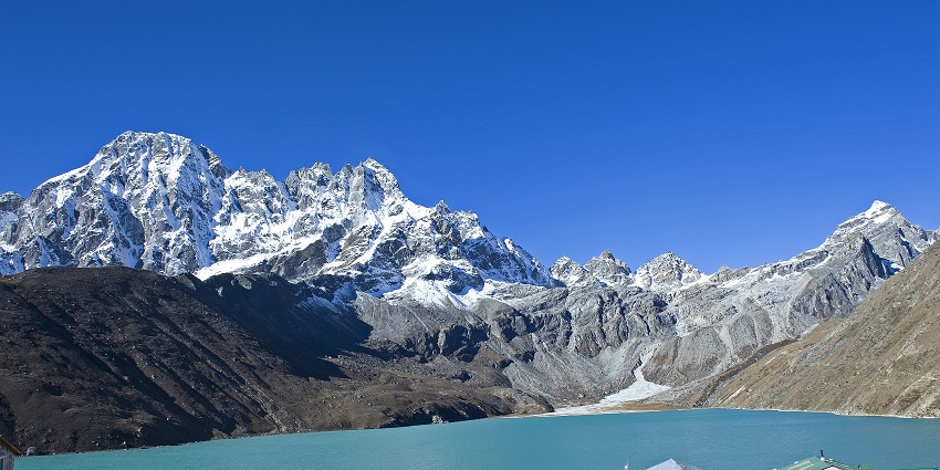 An image of Gokyo Lake viewed from Gokyo, with clear water surrounded by rugged terrain.