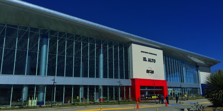 Passengers are walking outside El Alto International Airport while the sunlight is bright.
