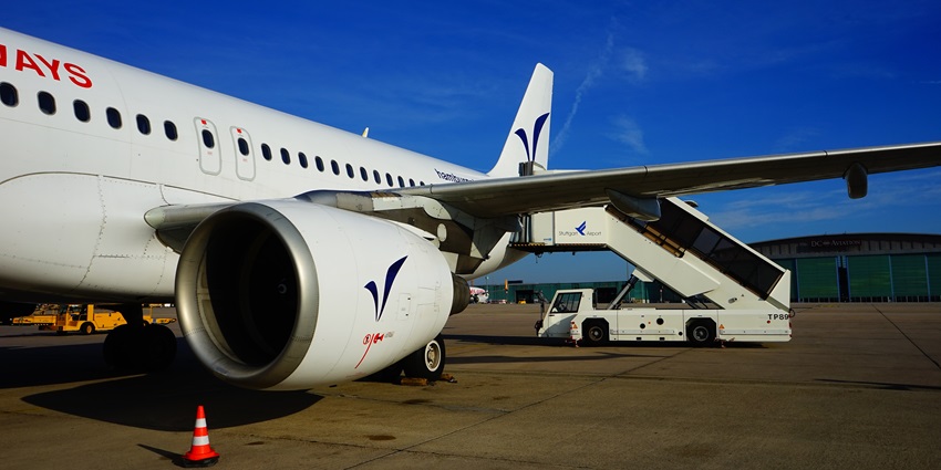 An aircraft is standing on the tarmac while mobile stairs are aligning for boarding.