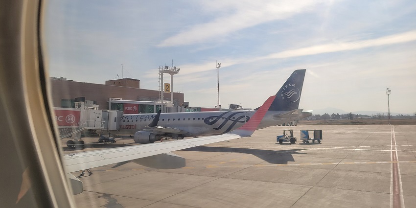 El Plumerillo International Airport terminal with runway, planes, and nearby buildings.