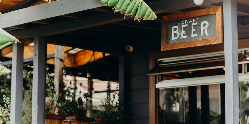 Craft beer bar showcasing a wooden sign above a glass window, displaying Dunedin nightlife.