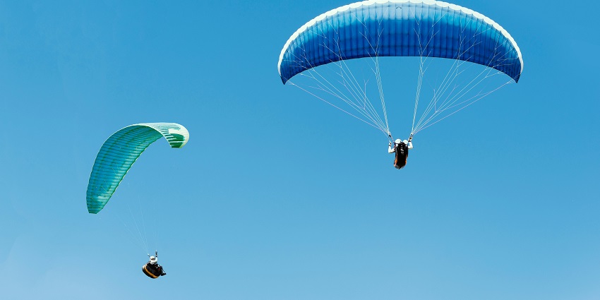 Two people enjoying mid-air above the blue lake and mountains