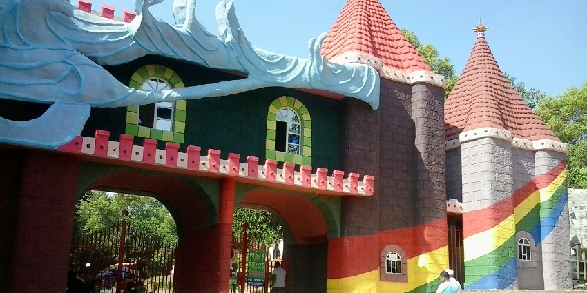 View of a colourful, castle-like structure with two red-roofed towers and playful design elements at the Water Kingdom in Mumbai