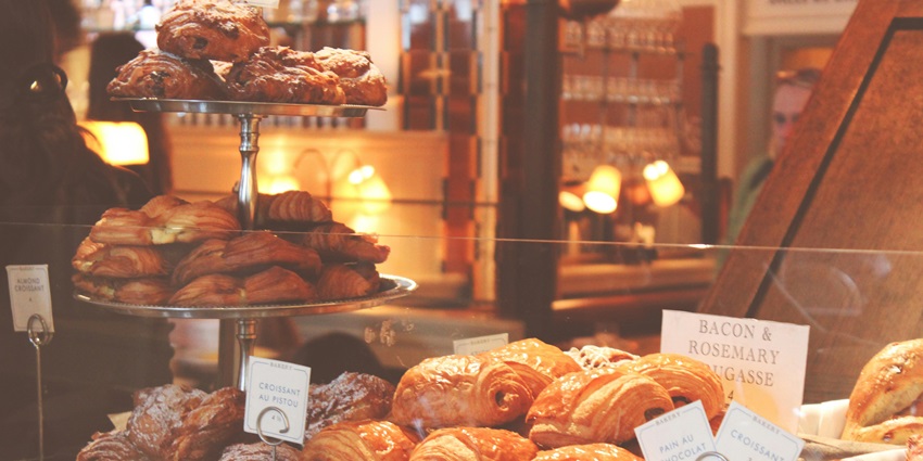 Different-flavoured croissants placed on different trays on display behind the glass.