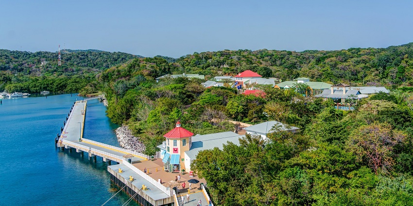 Tourists are walking along the wooden walkway at Roatán Welcome Center, enjoying the view