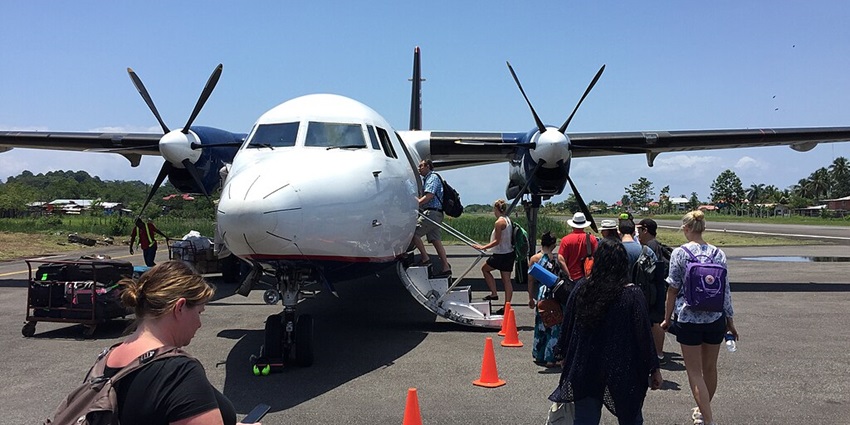 Front view of a Fokker 50 Panama Air with passengers boarding in line at the airport