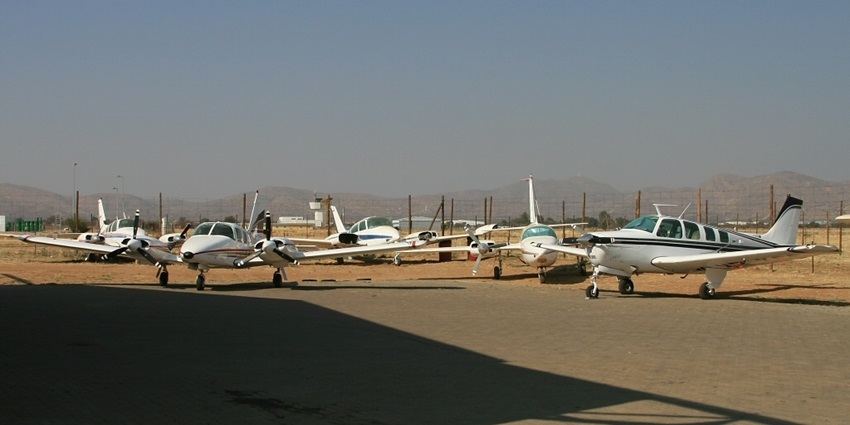 A small aircraft is taxiing on the runway at Windhoek's Eros Airport under a clear sky.
