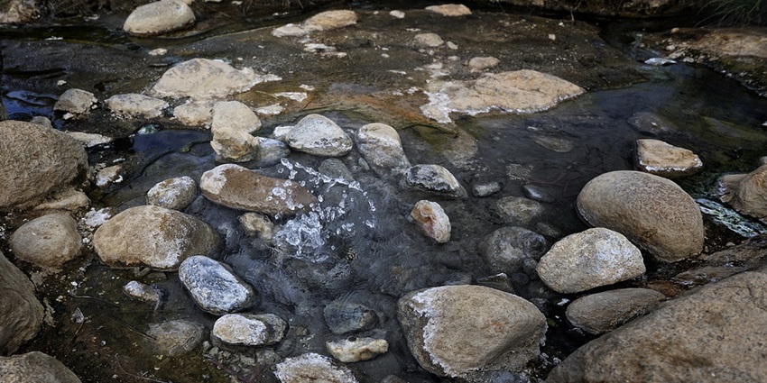 A picture of a naturally occurring hot spring in Paro with stones all around the place