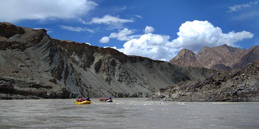 Two yellow rafts on a river, during river rafting in Ladakh, surrounded by rocky mountains.