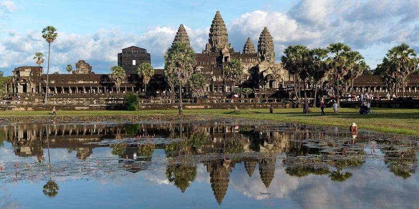 An image of Angkor Wat against a gradient sky with glowing sunrise hues and reflections