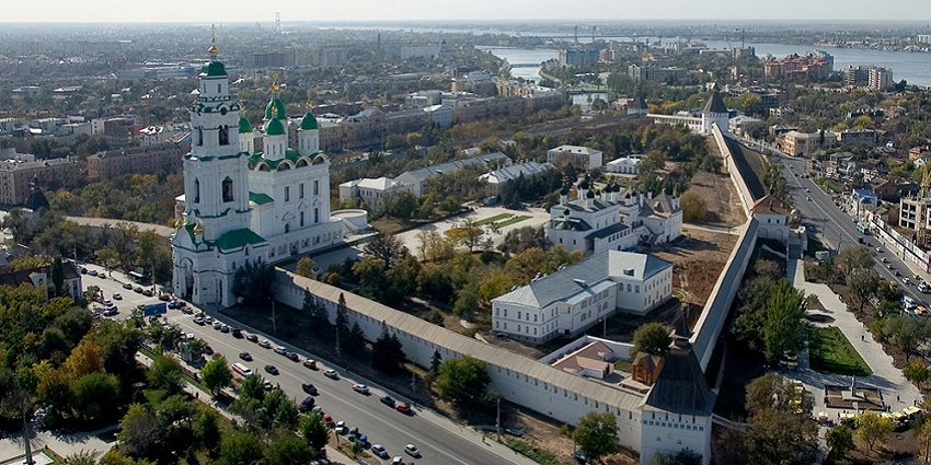 Aerial view of historic Astrakhan with white walls, towers, domes, and a nearby river