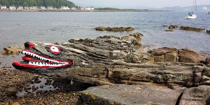 A picture of a crocodile-shaped rock in Sri Lanka, with decorations and surrounding waters