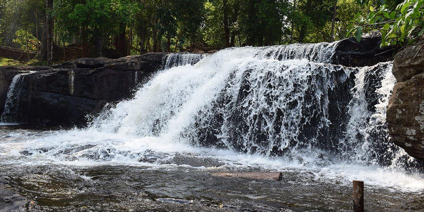 An image of visitors enjoying Kulen Mountain Waterfalls, surrounded by flowing water and greenery.