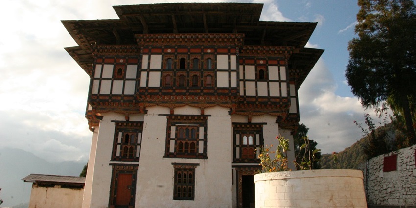 Nalanda Buddhist Institute with monks in red robes and prayer flags in a serene hill setting.