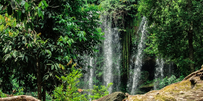 Scenic waterfalls and forested trails in Phnom Kulen National Park with ancient ruins nearby.