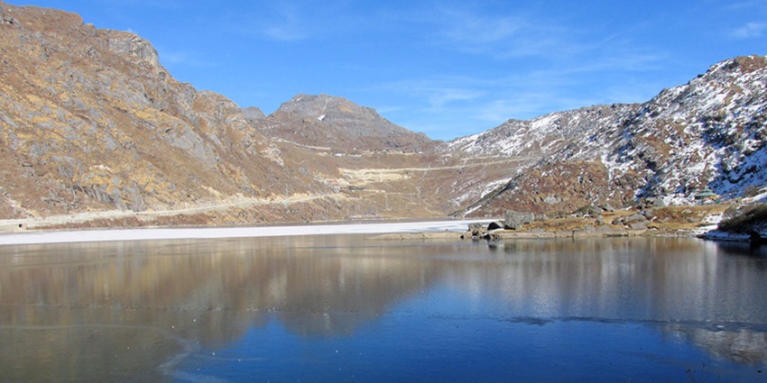 Changu lake with a still water body surrounded by snow-covered mountains