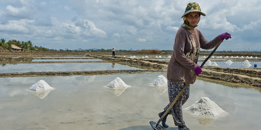 An image of a woman working in the salt fields in Kampot, Cambodia.