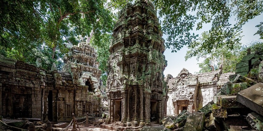 An image of a tall, intricately carved, Ta Prohm, surrounded by overgrown trees, one of the best things to see in Cambodia in April.