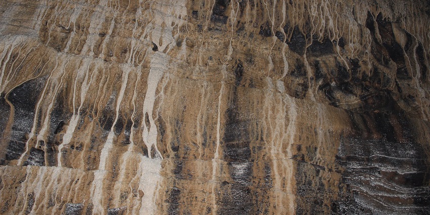 The textured rock wall of Gupteshwor Cave in Nepal showcases stunning natural formations