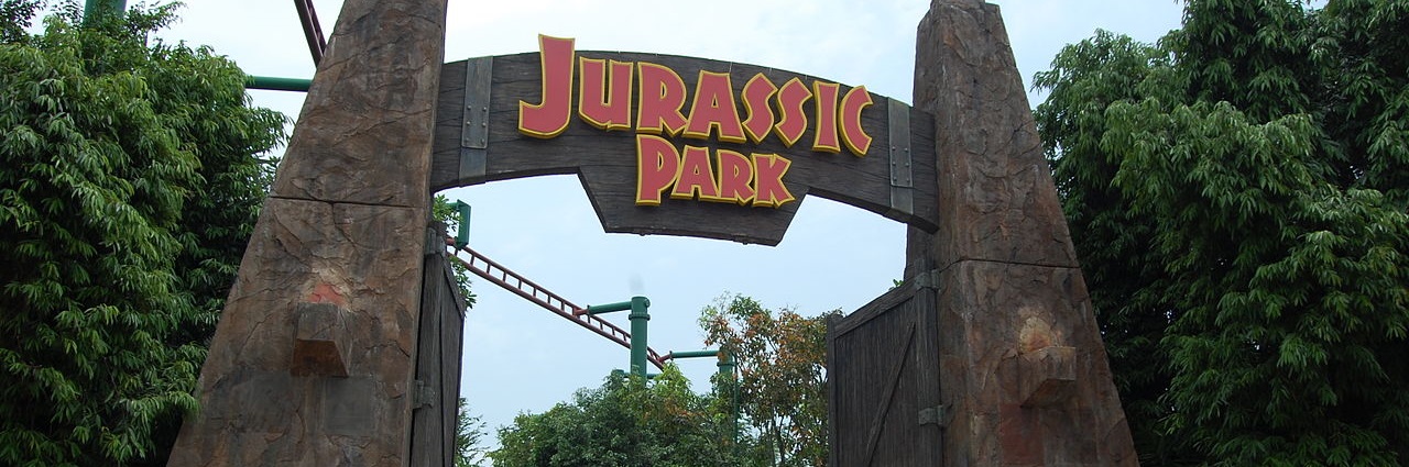 Jurassic Park entrance at Universal Studios Singapore, with people walking under the gate