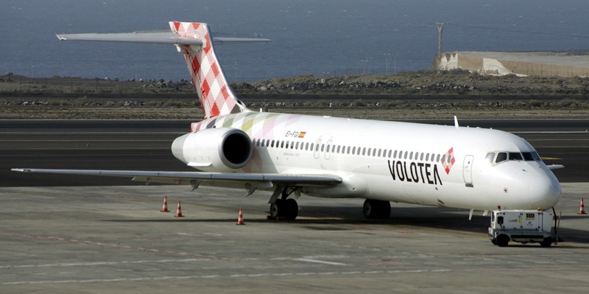 A small power source near a gigantic Boeing 717-2 flight taxied near a runway