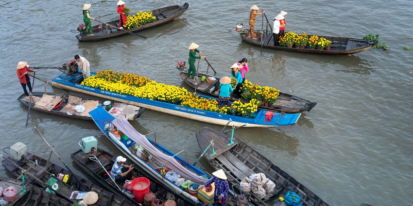 Vendors selling bright flowers from wooden boats at the shopping hub of Thailand.