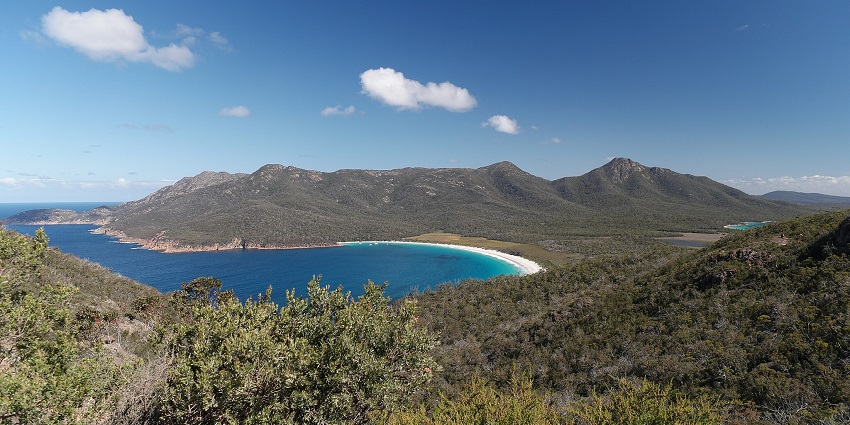 Aerial view of Freycinet National Park, with its coastline, featuring a clear blue sky in the background