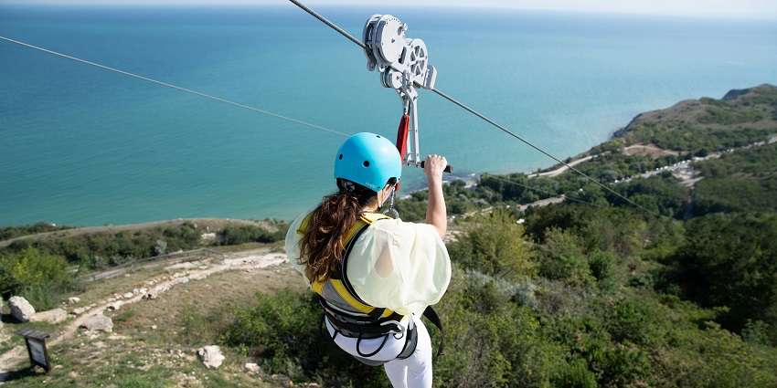 Ziplining over lush greenery with a stunning ocean view, a thrilling thing to do in Kalba