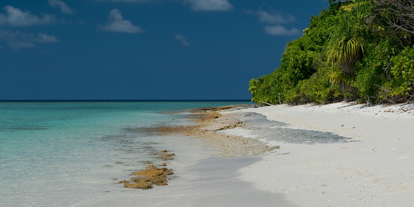 An image of a remote island beach with untouched white sands and shallow turquoise waters